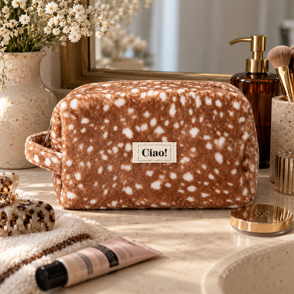 Flauschige braune Kosmetiktasche mit weißem Reh-Print, Reißverschluss, seitlicher Trageschlaufe und cremefarbenem Ciao!-Label.