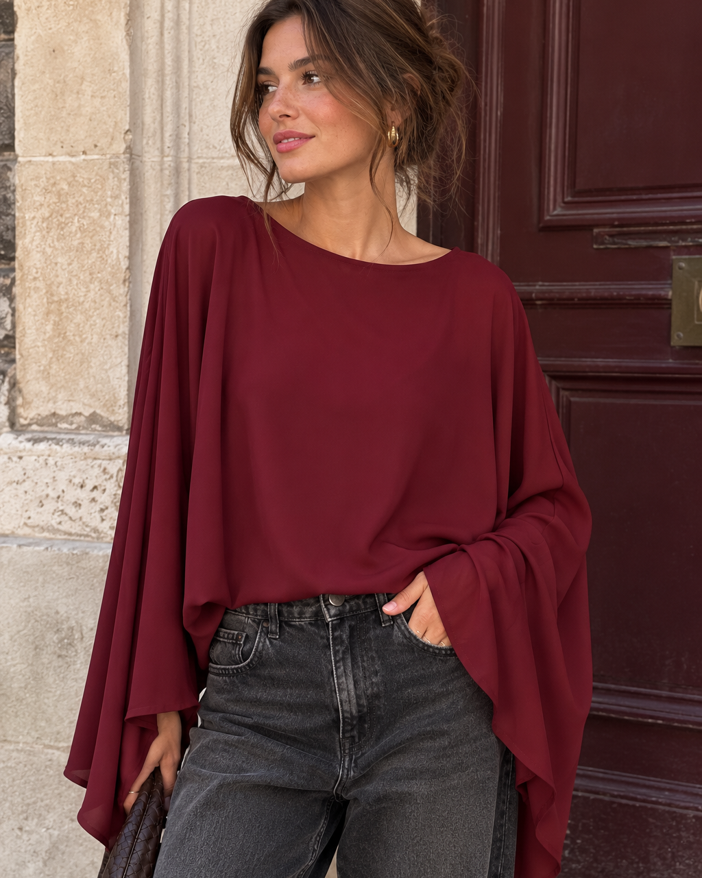 bordeauxrote Bluse mit fließenden Fledermausärmeln zu einer dunkelgrauen Jeans im eleganten Streetstyle.